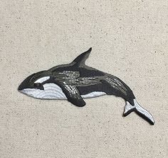 an orca whale embroidered onto the side of a piece of fabric