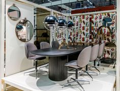 a round table surrounded by chairs and mirrors