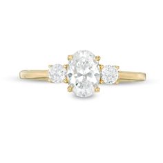 a three stone engagement ring in yellow gold with an oval diamond center and side stones