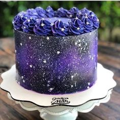 a purple and black cake sitting on top of a white plate