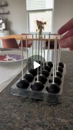 a person is placing chocolate candies in an ice tray on a table with plates and flowers