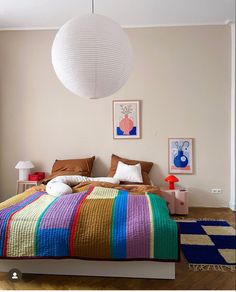 a bedroom with a bed, lamps and pictures on the wall in front of it