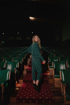 a woman standing on top of a red carpet in front of rows of green chairs