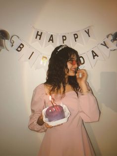 a woman in a pink dress holding a birthday cake