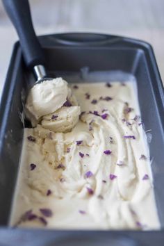 a scoop of ice cream with lavender sprinkles in a black container on a table