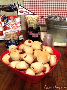 a red bowl filled with pigs in a blanket next to other snacks and condiments