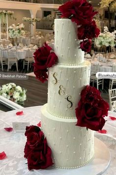 a three tiered white wedding cake with red flowers