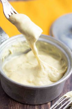 a spoon full of mayonnaise being lifted from a can with a fork in it