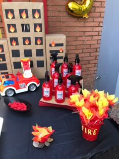 a table topped with red and yellow firetrucks next to a brick wall