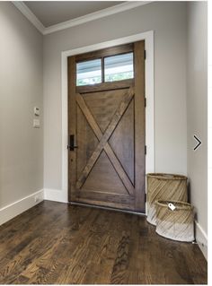 an empty room with a wooden door and basket on the floor in front of it