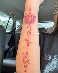 a woman's arm with a lotus tattoo on her left wrist and the word love written in red ink