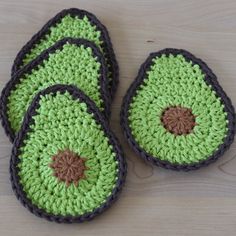 four crocheted slippers are sitting on a wooden surface, one is green and the other is brown