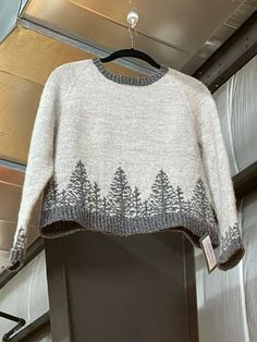 a sweater with trees on it hanging from a rack