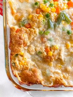 a casserole dish with vegetables and meat in it on a white table cloth