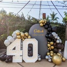 the balloon arch is decorated with black, gold and white balloons that spell out 40