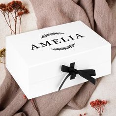 an open white box with the name amelie on it and black ribbon around the lid