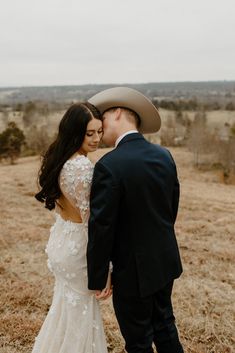 a bride and groom are standing in a field with their heads touching each other's foreheads