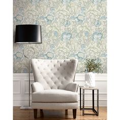 a white chair sitting in front of a lamp on top of a wooden floor next to a wall