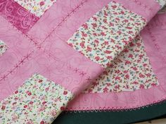 a pink and white quilt with flowers on it