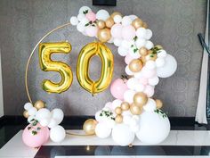 the 50th birthday balloon arch is decorated with gold, white and pink balloons that spell 50