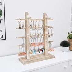 a wooden jewelry rack with earrings hanging from it's sides on top of a white counter