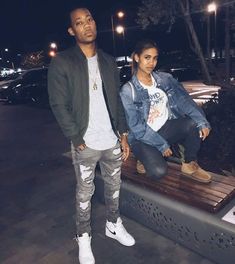 a man and woman sitting on top of a bench next to each other at night