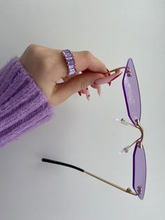 a woman's hand holding up some purple sunglasses