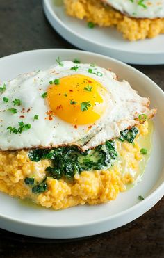 two white plates topped with eggs and spinach