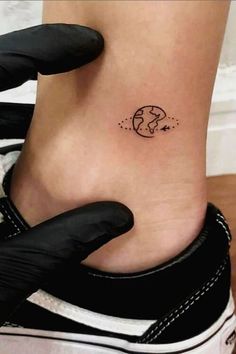 a woman's foot with a small earth tattoo on the left side of her ankle