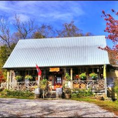 a small house with porches and flowers on the front door is surrounded by trees