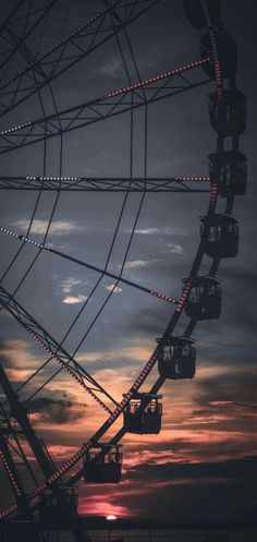 a ferris wheel with the sun setting behind it