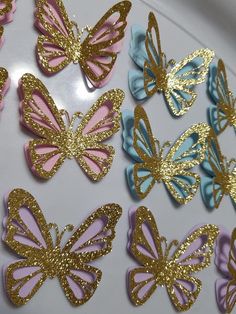 there are many different colored butterflies on the table with gold and blue glittered wings