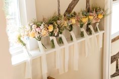 a row of flowers sitting on top of a window sill next to a white wall