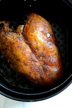 a cooked chicken in a black pot on a white counter top with the lid open