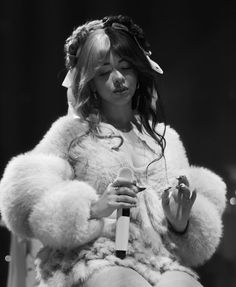 a woman in a fur coat holding a microphone