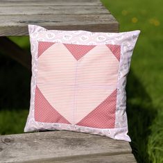 a pink heart pillow sitting on top of a wooden bench