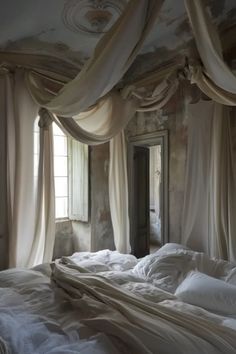 an unmade bed with white sheets and drapes