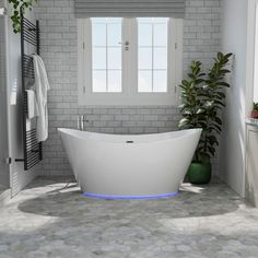 a white bath tub sitting in a bathroom next to a window and potted plant