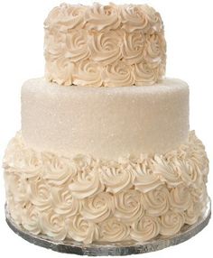 a three tiered cake with white frosting roses