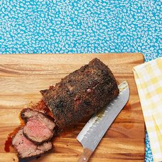 a large piece of meat sitting on top of a cutting board next to a knife