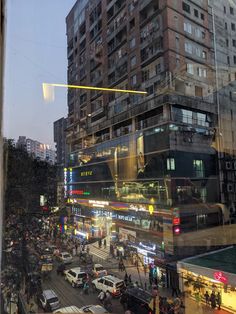 a city street filled with lots of traffic next to tall buildings in the evening time