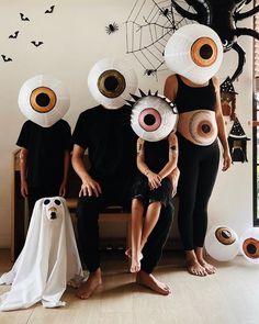 three people in halloween costumes sitting on a bench with their faces painted to look like eyes