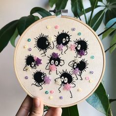 someone is holding up a cross stitch embroidery project with little black and white creatures on it