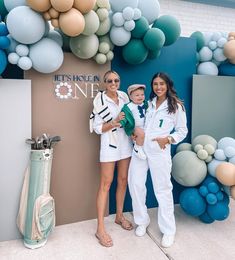 two women and a boy are posing for a photo in front of a balloon wall