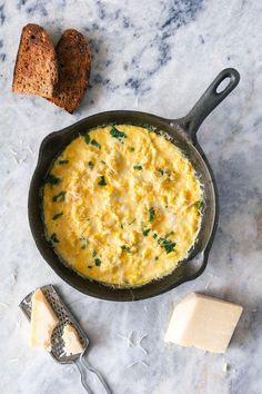 an omelet in a cast iron skillet next to bread and butter