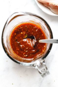 a blender filled with red sauce on top of a white counter next to meat