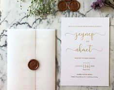 the wedding stationery is laid out on a marble table with purple flowers and greenery