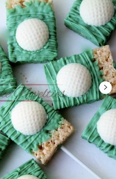 some green and white desserts are arranged on a plate with toothpicks in the shape of golf balls