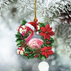 a flamingo christmas ornament hanging from a tree with pine cones and poinsettis