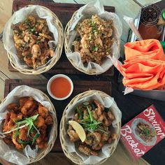 four baskets filled with food sitting on top of a wooden tray next to a drink